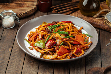 Portion of oriental dish tsomyan roasted noodles on wooden background