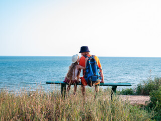 Happy father and daughter sitting on bench on marine landscape back view. Dad and child having fun walking together looking at the sea from above.Lifestyle real people. Happiness family travel concept