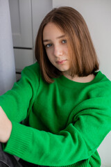 Naklejka premium portrait of an attractive teenage girl sitting on the windowsill. romantic person. High quality photo