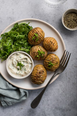 Assiette de patates hasselback rôties au four avec salade, épices et sauce creamy