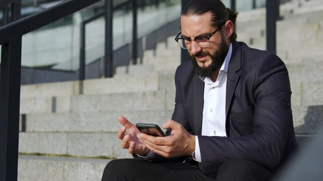 Anxious bearded man typing on smartphone, trying to cancel business meeting