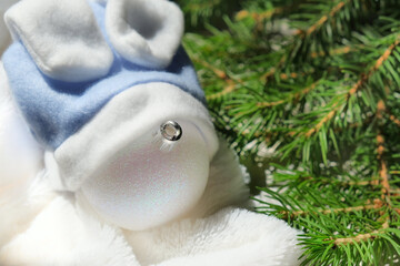 Christmas still life, Funny white Christmas toy ball with hat like a bunny on fluffy plaid and fir branches