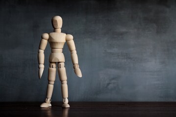 Wooden human figure standing in the dark room. Copy space for text