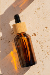 Amber glass dropper bottle with bamboo lid on stone plate. Skincare cosmetic. Beauty concept for face body care