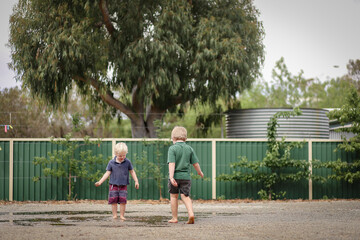 Two little boys jumping and splashing in puddles after rain