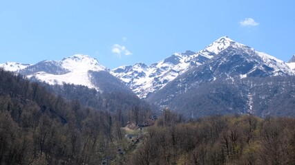 Obraz premium picturesque landscape of snow-capped mountains with white clouds on a blue sky on a sunny day at Krasnaya Polyana in Sochi, Russia