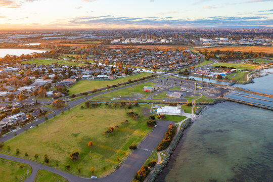 Aerial view of coastal reserve and parkland next to a calm bay at sunset
