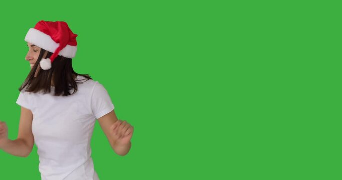 Enthusiastic woman in santa hat dancing over green background