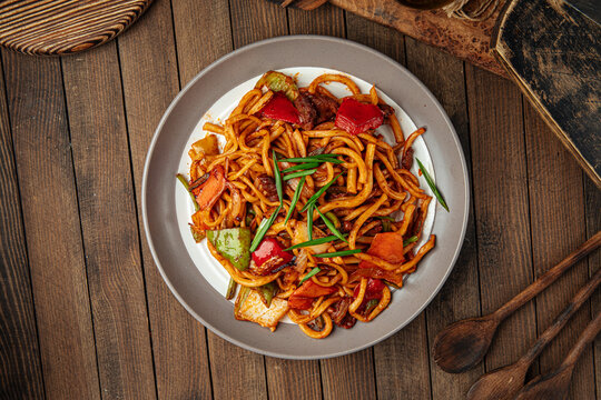 Portion of oriental dish tsomyan roasted noodles on wooden background