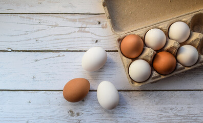 Chicken eggs in a cardboard storage on a light wooden background. Purchase and storage of eggs. healthy breakfast ingredient. Top view, flat lay.