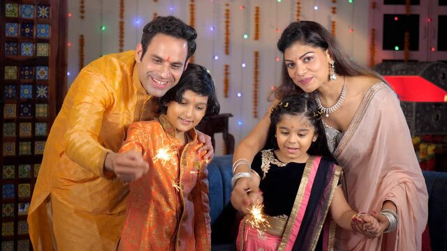 Small nuclear family burning firecrackers / Phuljhadis with their children - festive season. Happy family celebrating the festival of Diwali together at home - a Hindu festival  an auspicious occas...