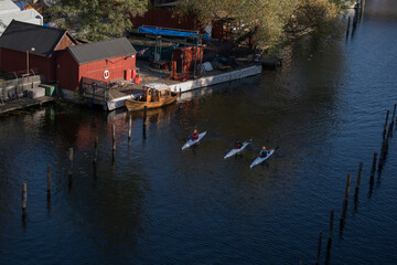 The channel P&aring;lsundet in Stockholm an colorful autumn canoes passing winter empty piers and timber piles.