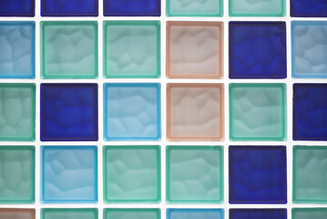 glass block wall in different colours, blue, salmon and green.
