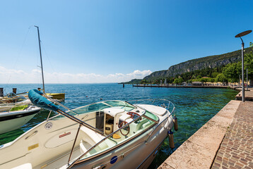 Fototapeta premium Port of the small town of Garda, tourist resort on the coast of Lake Garda (Lago di Garda). Beautiful bay with the Promontory of San Vigilio (Punta San Vigilio). Verona province, Veneto, Italy, Europe