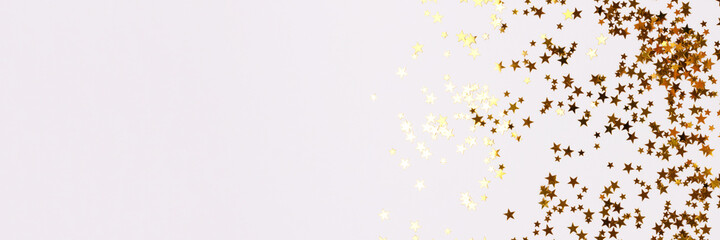 Fototapeta na wymiar Banner with gold colored stars confetti scattered on a white background with place for text.