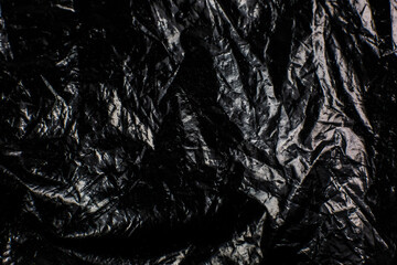 Crumpled Black Plastic Bag texture background. Glossy polyethylene overlay