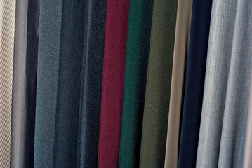 Texture of multicolored fabrics close up. Fabrics for sewing clothes hang in the store. Many fabrics of different materials, colors and textures.