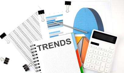 Obraz premium Text TRENDS on a notebook on the diagram and charts with calculator and pen