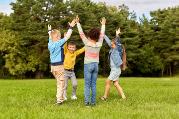 Fototapeta premium childhood, leisure and people concept - group of happy kids playing round dance at park