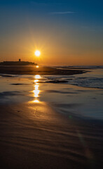 Reflections of the sun on the sand in the early morning. Carcavelos Beach near Lisbon in Portugal.