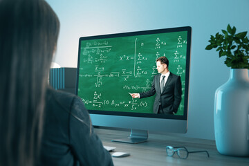 Obraz premium Young business woman at office desk looking at computer screen with online education chalkboard and formulas pattern. Digital knowledge and webinar concept.