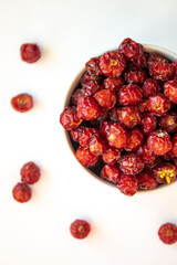 Sun-dried wild rose hip in a white bowl on white background