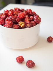Sun-dried wild rose hip in a white bowl on white background