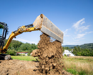 Mini excavator digging preparing ground under home garden © leszekglasner