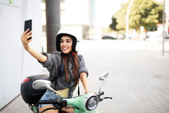 Beautiful woman getting ready for a ride on scooter. Beautiful happy lady taking selfie photo