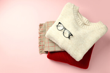 Sweaters and scarf with glasses on pink background