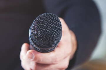 A journalist takes an interview by holding out a microphone. The concept of mass media and the press