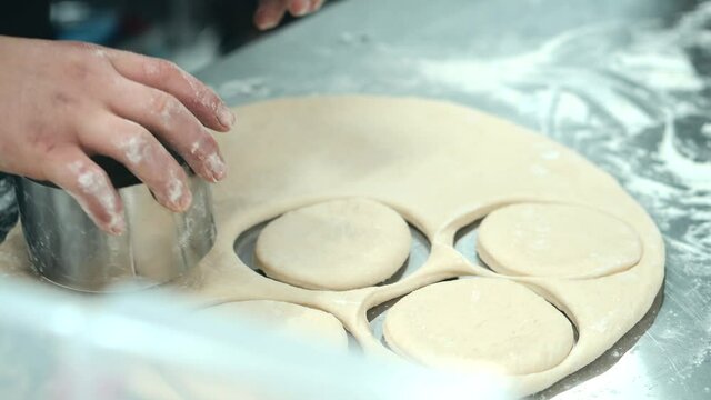 Footage of chef making round forms with dough for donuts. High quality 4k footage