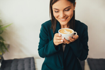 Young woman drinking cappuccino sitting in a cozy coffee house.