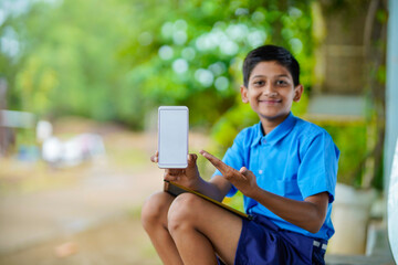 Indian school boy showing smartphone screen. online education concept.