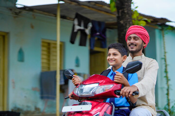 Young indian farmer dropping his child to school on bike