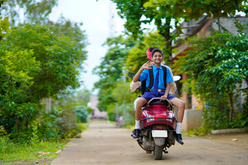Young indian farmer dropping his child to school on bike