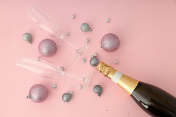 Bottle of champagne, glasses and baubles on pink background