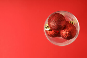 Champagne glass with baubles on red background