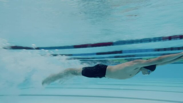 Underwater shot of swimmers in water immersion phase, sliding below the water surface and transition to swimming.