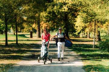 Golfing couple enjoying a beautiful day on the golf course. Walking between the holes