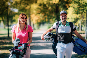 Fototapeta premium Couple on the golf course, walking to the next hole, enjoying a beautiful sunny autumn day