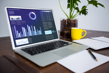 Laptop lying on desk with statistical data on screen