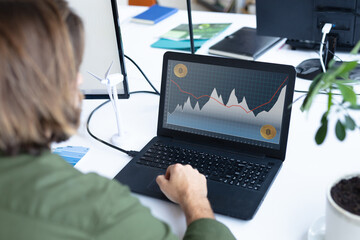 Caucasian businesswoman sitting at desk, using laptop with statistical data on screen