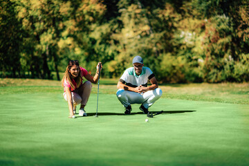 Fototapeta premium Golf lifestyle. Young couple having fun on the golf course