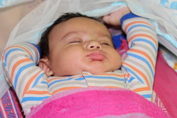 An Indian little newborn innocent baby sleeping in a funny way
