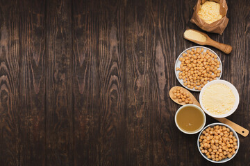Cooked Chickpeas, aquafaba, chickpea flour on dark wooden background.