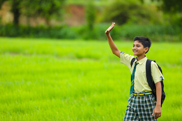 Indian school boy at green onion agriculture field.