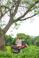 indian farmer standing with his bike at agriculture field