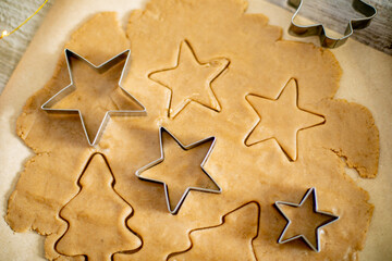 Top view of raw dough for cookies, cookie cutters and festive decoration on wooden table.