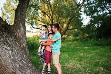 Naklejka na ściany i meble Happy young family: mother, father, two children son on nature having fun.